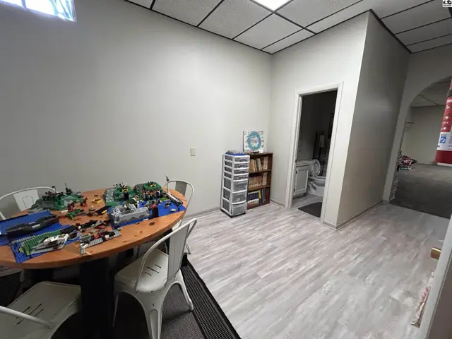 This room features a round table, four chairs, and a doorway leading to a bathroom.