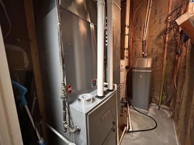 A large grey furnace and water softener are installed in a utility room.