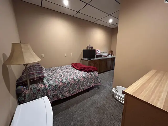This room features a bed, dresser, television, and a laundry basket.