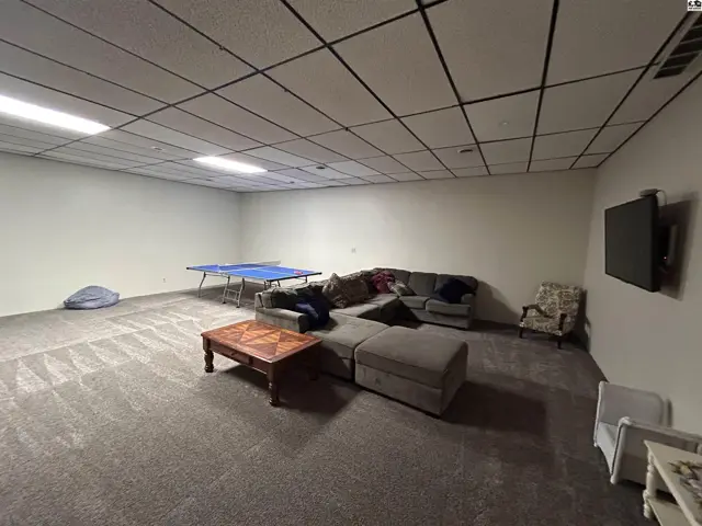 Spacious room with carpet, a sectional sofa, coffee table, and ping pong table.