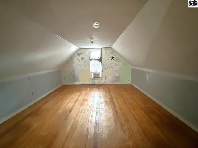 Attic space features sloped ceilings, hardwood floors, and a small window.