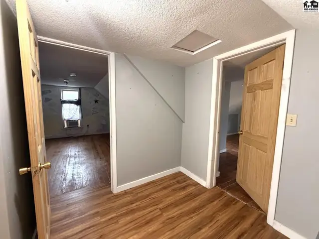 Hallway with wood-look flooring and two interior doors leading to rooms.