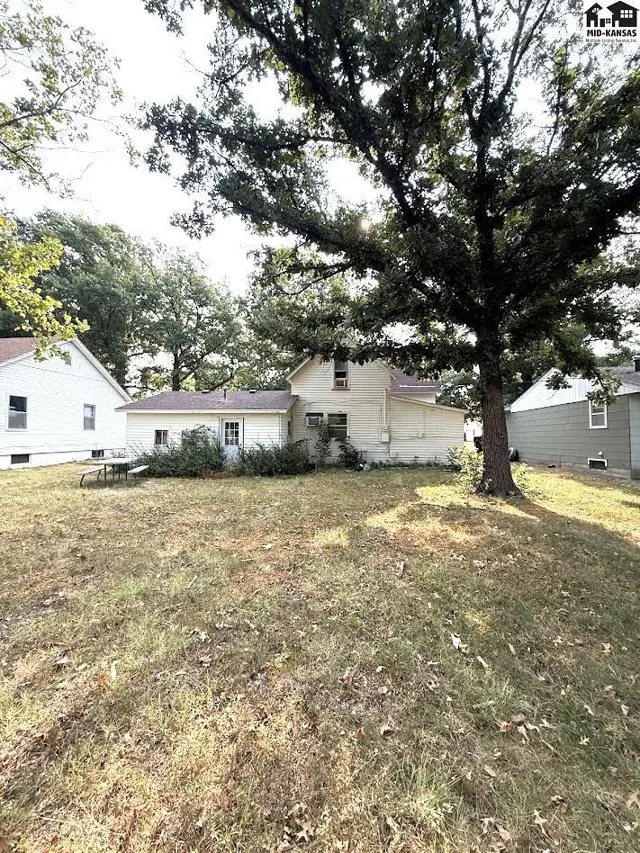 This property features a detached garage, a large tree, and a grassy yard.