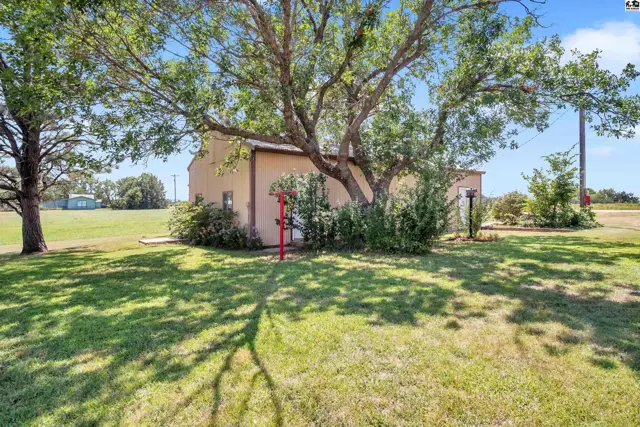 This tan stucco building sits on a grassy lot with mature trees.