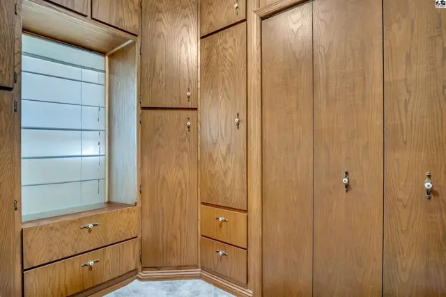 Built-in wooden cabinets with drawers and a display shelf line the walls of this room.