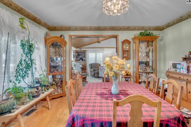 Formal dining room with wood floors, glass display cabinets, and a plaid-covered table.