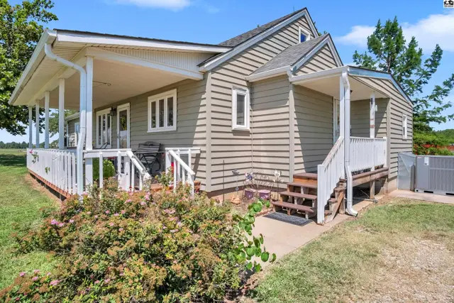 This home features a covered front porch with white railings and a side entrance with wooden steps.