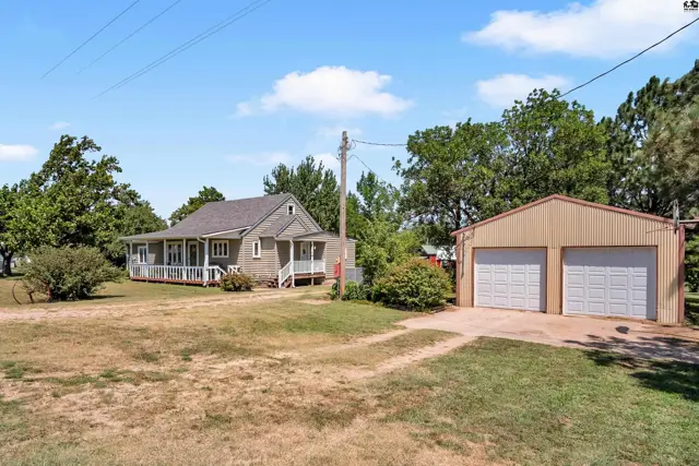 This property features a two-story house with a wraparound porch and a detached two-car garage.
