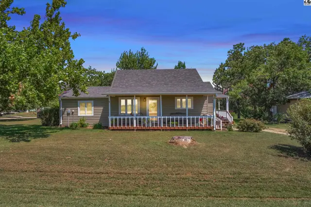 This home features a covered front porch with white railings and a gently sloping lawn.