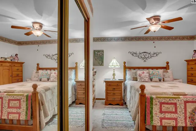 Two beds with wooden frames are in a room with mirrored closet doors.