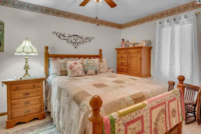 This bedroom features a wooden bed frame, a quilt, and a dresser.