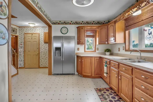 Spacious kitchen features wood cabinetry, stainless steel appliances, and a patterned floor.