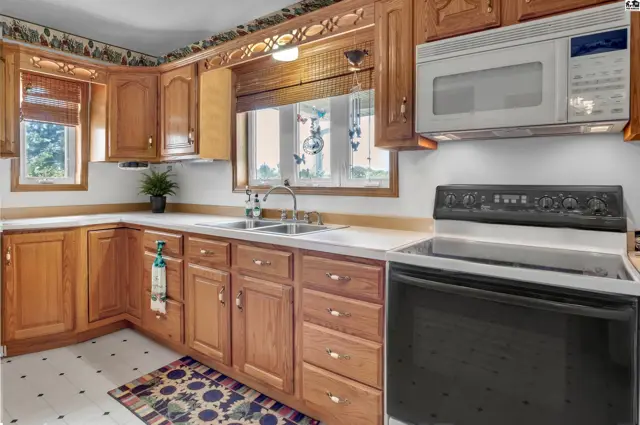 This kitchen features oak cabinetry, a double sink, and a black electric range.