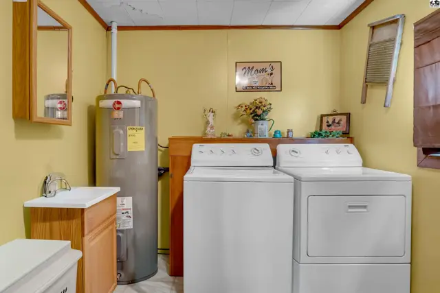 Laundry room with washer, dryer, sink, and water heater.