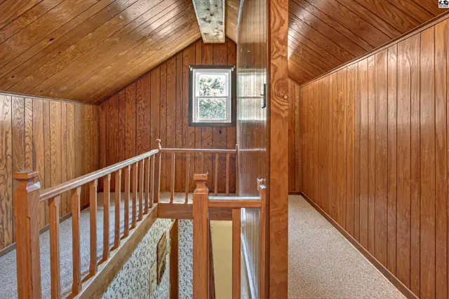 Wood-paneled walls and ceiling frame a small window and a wooden banister.
