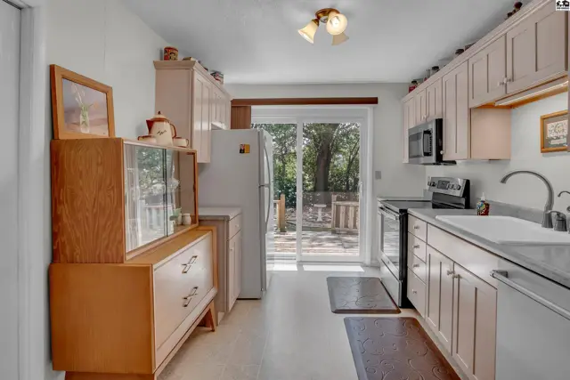 This kitchen features light wood cabinets, a white countertop, and a sliding glass door.
