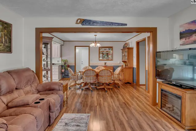 Wood-paneled archway connects a living area with a dining room and kitchen.