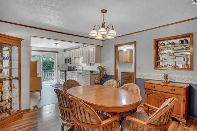 Oval dining table with six chairs in a room with hardwood floors and a chandelier.