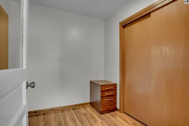This room features wood-look flooring, a white wall, and a sliding closet door.