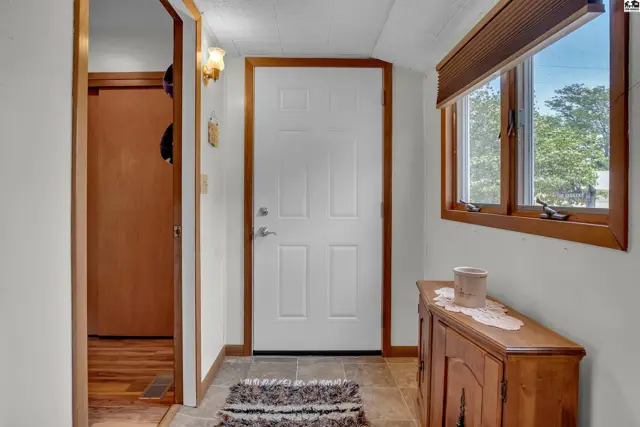 This entryway features a white door, wood-toned trim, and a wooden cabinet.