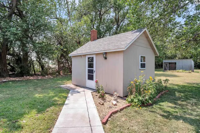 Small stucco building with a brick chimney and a concrete walkway.