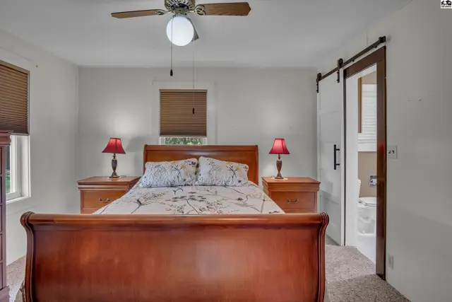 Spacious bedroom features a wooden sleigh bed, nightstands, and a sliding barn door.