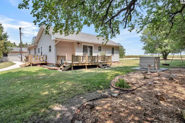 Exterior features a light-colored siding home with a wooden deck and mature trees.
