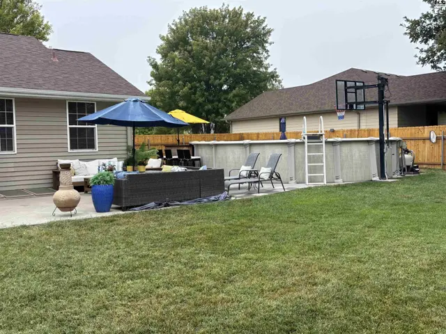 This backyard features an above-ground pool, patio furniture, and a basketball hoop.