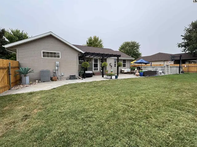 Spacious backyard features a pool, patio, pergola, and fenced perimeter.
