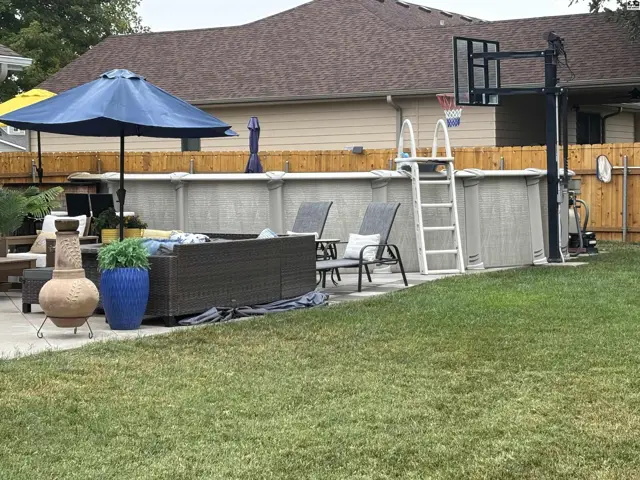 Above-ground pool with a deck, lounge chairs, and basketball hoop.