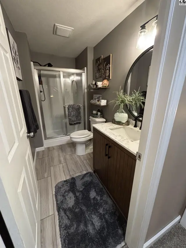 This bathroom features a walk-in shower, vanity with a marble countertop, and modern fixtures.