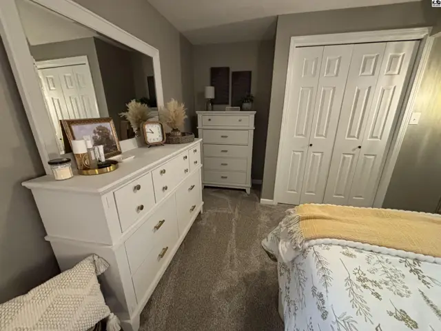 This bedroom features a white dresser with a large mirror and a closet with double doors.