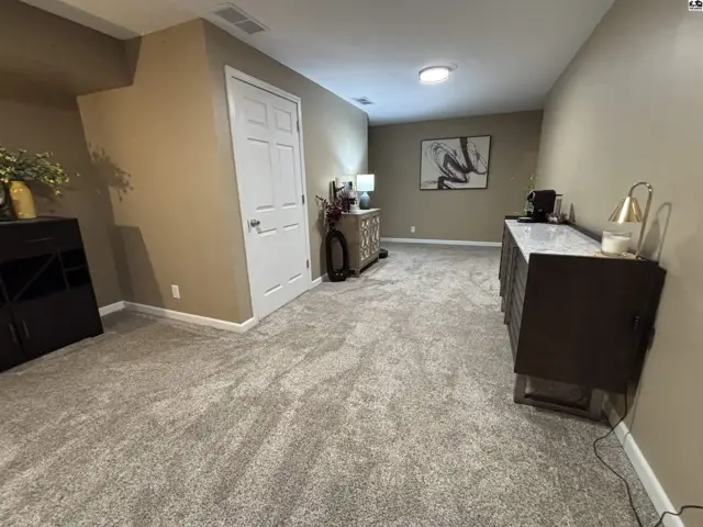 This room features plush carpeting, neutral walls, and multiple furniture pieces.