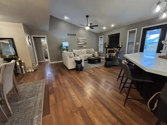 Spacious living area with vaulted ceilings, hardwood floors, and a large island.