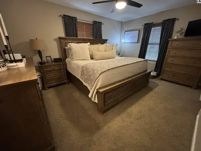 Spacious bedroom with a king-size bed, carpeted floors, and dark curtains.