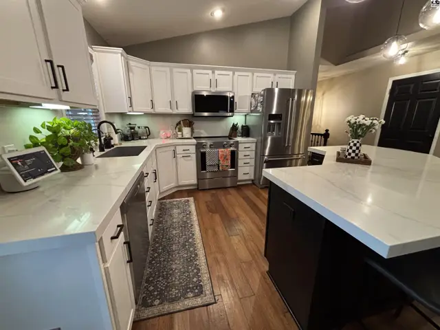 Modern kitchen features white cabinetry, stainless steel appliances, and a large island.