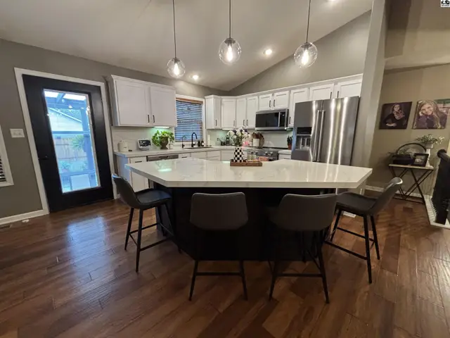 Spacious kitchen features a large island, white cabinetry, and stainless steel appliances.