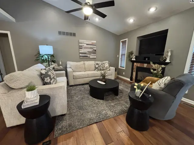 Spacious living room features a vaulted ceiling, fireplace, and hardwood floors.