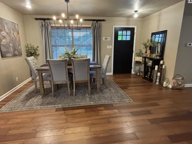 This dining room features a wood table, upholstered chairs, and a chandelier.