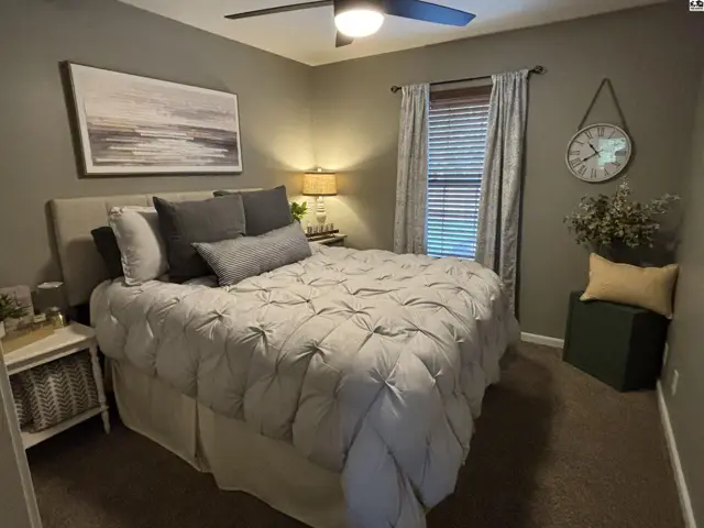 This bedroom features a queen-size bed, plush carpeting, and a ceiling fan.