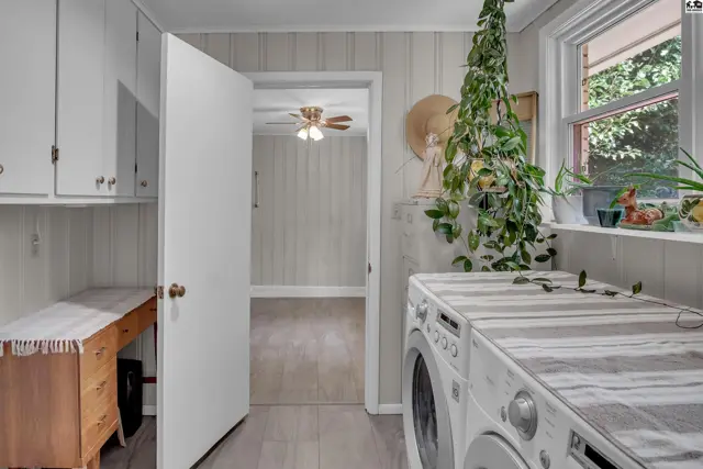 Laundry room with built-in cabinets, a desk, and a washing machine.