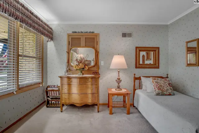This bedroom features a dresser, a bed, and a window with blinds.