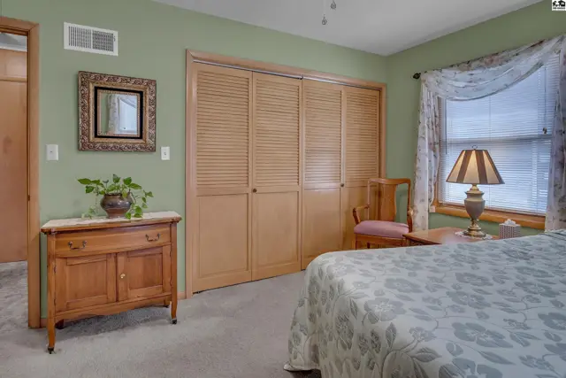 This bedroom features a large closet with louvered doors and a window with a floral curtain.