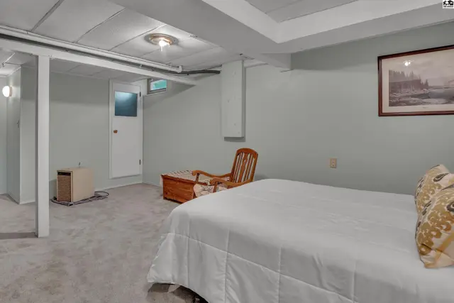 This room features a bed, wooden chair, and a framed picture on the wall.