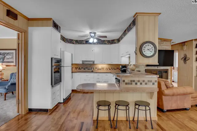 This kitchen features white cabinetry, a breakfast bar, and wood flooring.