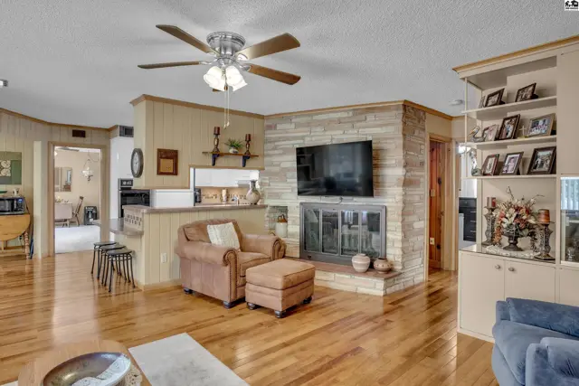 Spacious living area features a stone fireplace, built-in shelving, and hardwood floors.