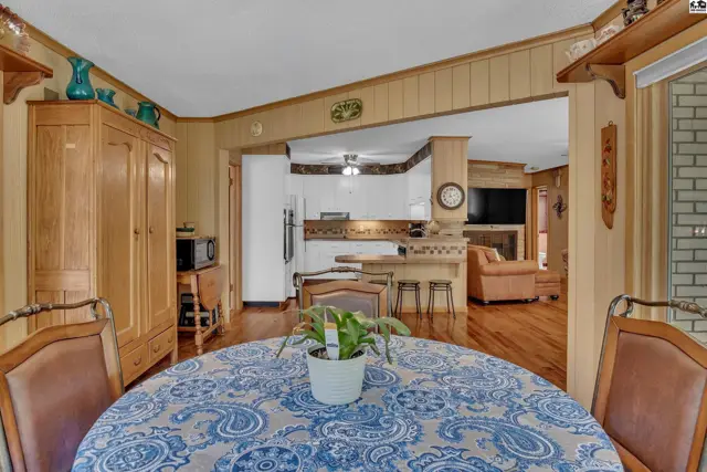 Wood-paneled dining area opens to a kitchen with white cabinets and a living room.