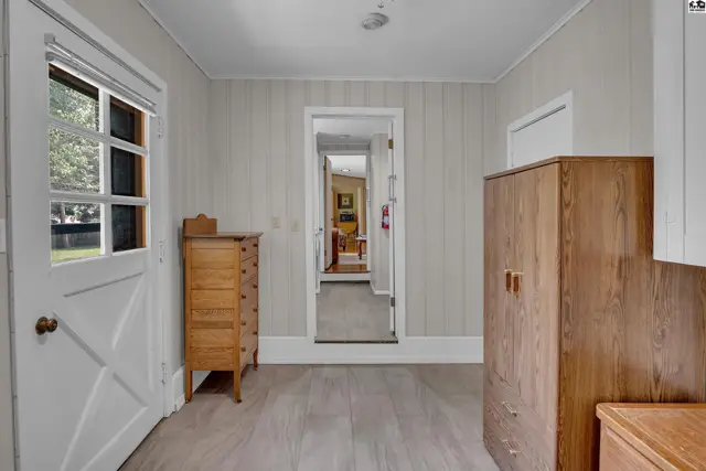 This hallway features wood-look flooring, a glass-paned door, and two wooden cabinets.