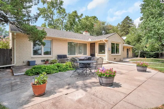 Brick ranch home with a large patio and mature trees.