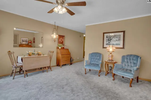 This living area features a dining table, two upholstered chairs, and a wooden desk.